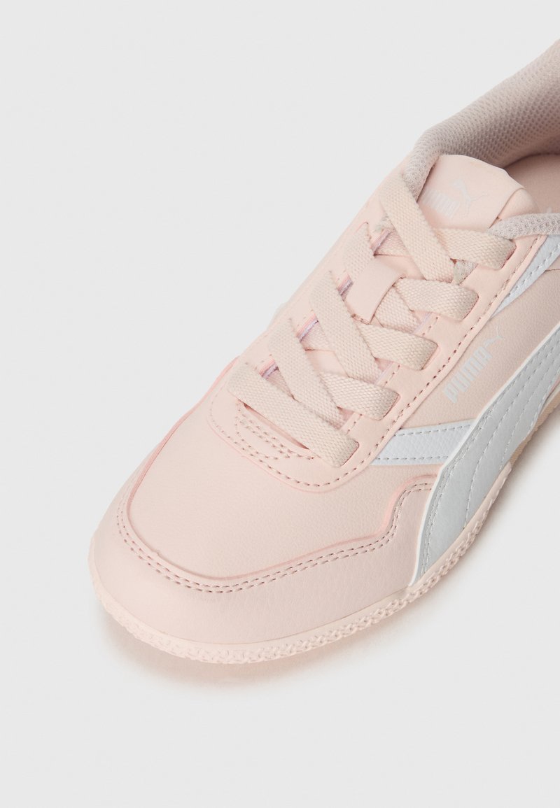 Zapatilla deportiva de color rosa claro con parte superior sintética, puntera redonda, diseño con cordones, detalles plateados y suela texturizada.