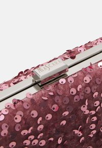 Clutchväska täckt med rosa paljetter med en metallisk spänne märkt "MASCARA." Rektangulär form med en mjuk textur.