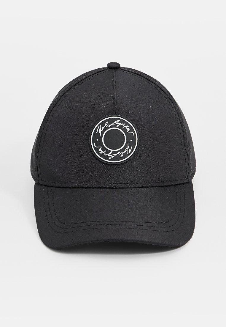 Casquette noire en tissu lisse, avec une visière arrondie et un patch de logo circulaire à l'avant, orné de lettres blanches et d'un cercle en contour.