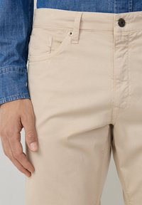 Beige katoenen broek met een rechte pasvorm, voorzien van een knoopsluiting, reguliere zakken en een gladde, licht glanzende structuur.