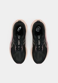 Zwarte sportschoenen met een gestructureerde bovenkant, roze accenten op de zool en zwarte veters. Heeft een logo en een patroonontwerp aan de zijkanten.