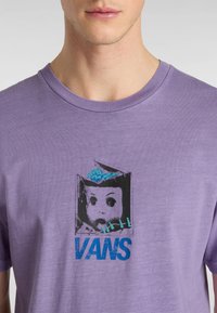 T-shirt di cotone viola con una grafica di una testa di bambola con un cervello, accentuata da lettering blu "VANS" e dettagli turchesi.