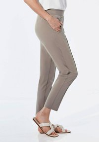 Lichtgrijze, taps toelopende broek met zijzakken en een brede tailleband, gecombineerd met beige sandalen met een geknoopt bandontwerp.