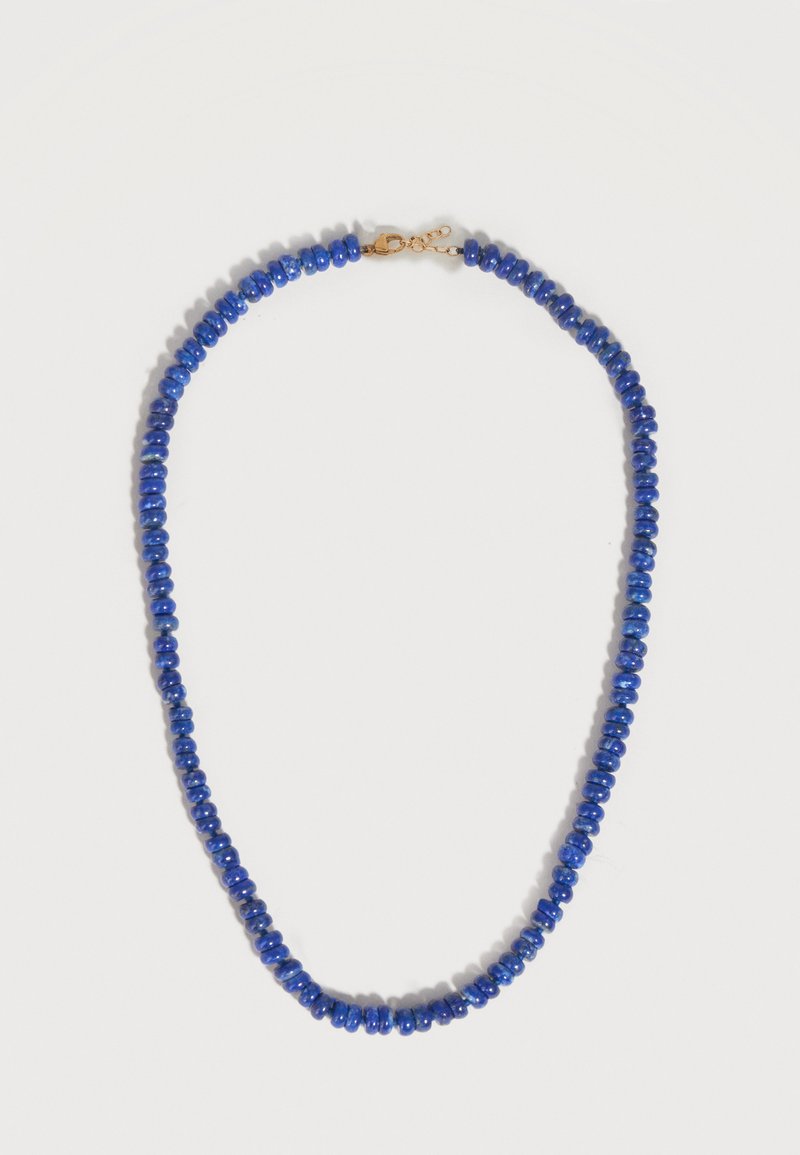 Perles bleues arrondies enfilées pour former un collier avec un fermoir de homard doré et une chaîne réglable sur un fond clair.