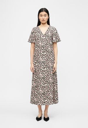 Woman with straight black hair wearing a pink, white, and black floral V-neck midi dress with short flutter sleeves and black pointed flats.