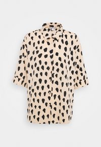 Kurzärmlige Bluse aus pfirsichfarbenem Stoff mit schwarzen unregelmäßigen Punkten, Knopfleiste und klassischem Kragen.