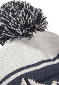 Strickmütze in Off-White und Navy Blau mit einem großen, strukturierten Pompon oben. Verfügt über ein Strickmuster und ein geripptes Band.