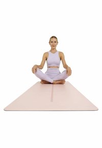 Yoga mat in lichtroze, plat met afgeronde hoeken. Model draagt een lichtpaars mouwloos topje en leggings, zittend in een gekruiste beenpositie.