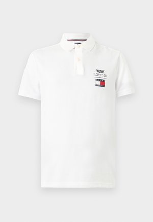 Polo blanc à manches courtes avec col et boutons, arborant les logos de l'équipe Cadillac Formula 1 et Tommy Hilfiger sur la poitrine gauche.