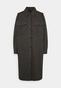 Svart och brun rutig skjortklänning med två bröstfickor, knappstängning framtill och krage. Tillverkad av ett texturerat tyg.