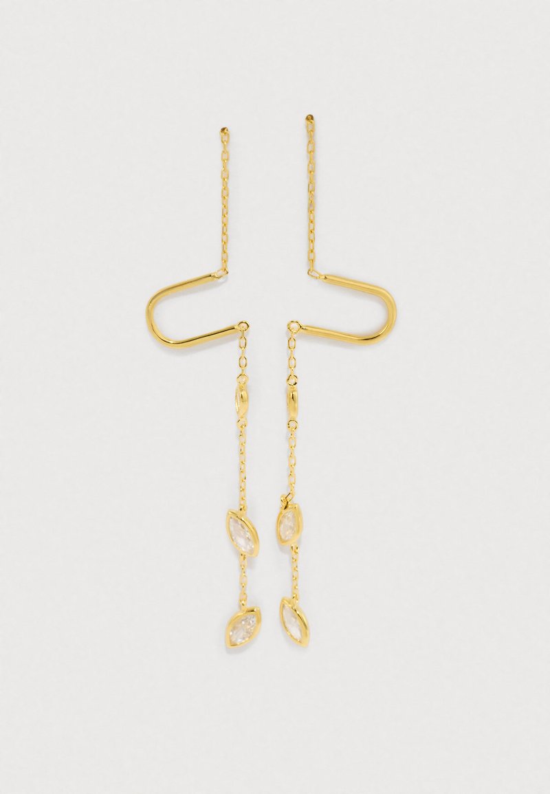 Brincos pendentes de cor dourada apresentam um design único em forma de U com corrente e detalhes transparentes em forma de navete.