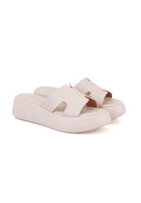 Sandales à plateforme beige clair en matériau lisse, dotées de larges sangles avec des découpes et d'un design à bout arrondi.