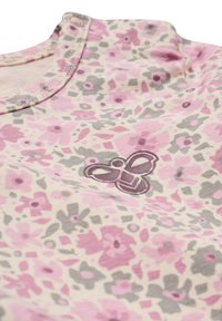 Lätt tygskjorta med blommönster i rosa, grått och krämfärgat, med en liten broderad logotyp av sammanflätade former nära halsringningen.