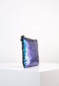 Paljetterad kuvertväska med iriserande lila paljetter på ena sidan, svart tyg på baksidan, dragkedjestängning och en smal rektangulär form.