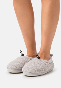 Gray fleece slippers with soft, textured exterior, rounded toe, and black accent loops; cushioned sole for comfort.