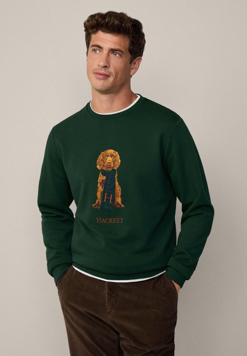 Sudadera de color verde oscuro hecha de algodón, que presenta un gráfico de un perro con una bufanda de tartán. Logo "Hackett" impreso debajo del diseño.