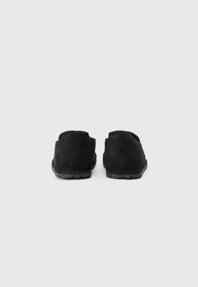 Zapatos de ante negro con un diseño de bajo en la parte trasera, puntera redonda y suela de goma texturizada. Detalle de costura a lo largo de la suela visible.