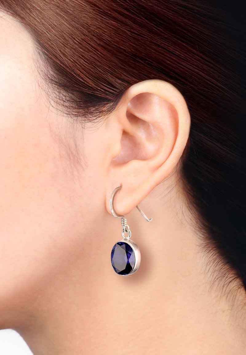 Sølv hoops ørering med en stor, facetteret oval blå sten. Indstillingen er strømlinet med en poleret finish og synlig wire hook.