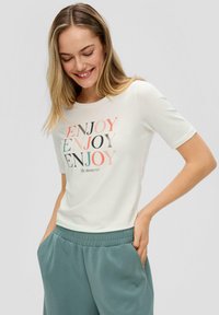 Witte korte mouwen t-shirt met kleurrijke "ENJOY" tekst in verschillende lettertypes, gecombineerd met lichtgroene joggerbroeken met elastische tailleband.