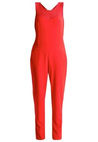 Combinaison rouge sans manches avec empiècement en dentelle, taille cintrée et pantalon droit.