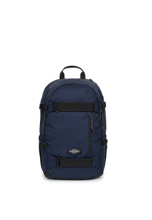 Sac à dos Eastpak bleu marine avec poche zippée à l'avant, bretelles réglables noires et poignée de portage supérieure sur fond blanc.