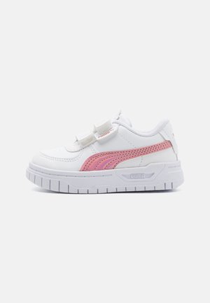 Baskets blanches pour enfants avec une bande rose Puma, double fermeture à scratch et semelle blanche épaisse sur un fond uni.