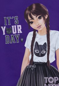 Sfondo viola con una maglietta grafica che presenta un design di un gatto nero e il testo "È il tuo giorno," abbinata a una gonna nera e capelli intrecciati.