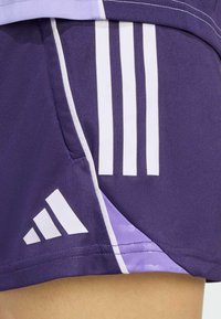 Purple athletic shorts with white diagonal stripes and Adidas logo. Features a textured, moisture-wicking fabric. Color gradient near hem.