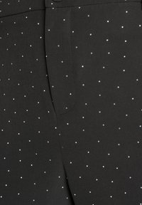 Black fabric pants featuring scattered silver dot embellishments, with a smooth texture and a fitted design. Includes front pocket detail.