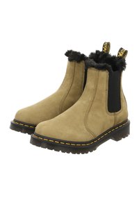 Sandfarbene Wildleder Chelsea-Stiefel mit einem schwarzen Kunstfellkragen, elastischen Seiteneinsätzen und gelben Nähten entlang der schwarzen Gummisohle.