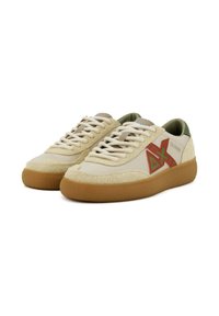Sneaker beige realizzati in materiali suede e canvas, dotati di suola in gomma, design con lacci, dettagli verdi nel tallone e un logo rosso.