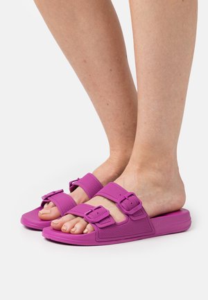 Fialové gumové sandály se dvěma nastavitelnými přezkami, otevřenou špičkou, texturovanými pásky a hladkou podrážkou pro pohodlí a snadné nošení.