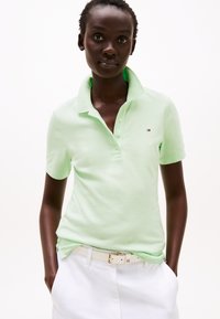 Lys grønn polo skjorte med brettet krage, to-knapp placket og lite logo. Kombinert med hvite shorts og et hvitt belte. Glatt tekstur.