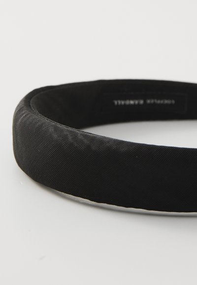 Black fabric headband with a smooth, textured surface, slightly padded, rounded shape, and a label on the interior.