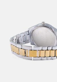 Silver and gold-tone stainless steel watch with a linked bracelet, square links, and a round case featuring a textured crown.