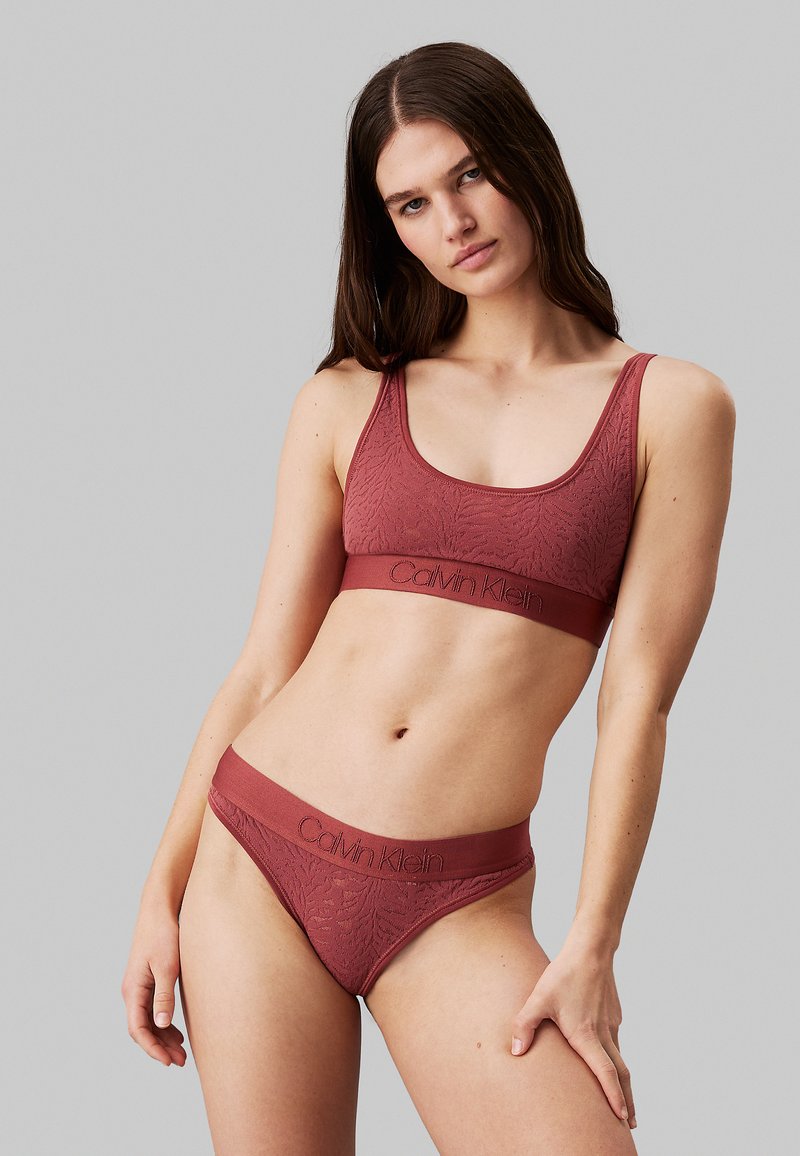 Bralette color bordeaux di Calvin Klein con un motivo testurizzato e fascia con logo, abbinato a uno string thong con un design simile. Tessuto morbido.