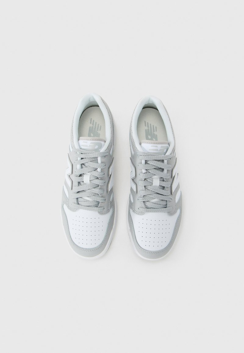 Pair of gray and white sneakers with laces, viewed from above on a white background.