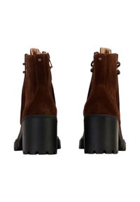 Botines de ante marrón con un tacón grueso negro, que presentan cremalleras laterales y acentos de herrajes en tono dorado para un detalle adicional.