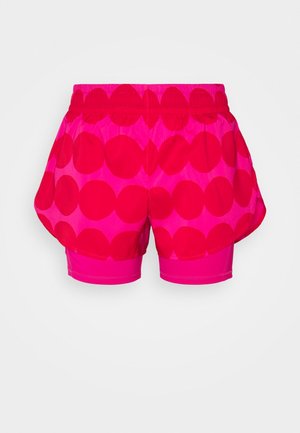 Shorts de sport roses à grands pois rouges, avec une ceinture élastique et un short intérieur ajusté visible en dessous.
