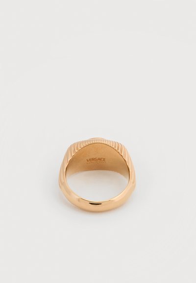 Δαχτυλίδι Versace σε χρυσούς τόνους με ραβδωτό σχέδιο στην κορυφή και λείο στρογγυλό δαχτυλίδι, με χαραγμένο το λογότυπο της μάρκας στο εσωτερικό.