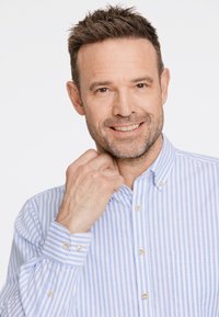 Vaaleansini-valko-raitaista nappikauluspaitaa, jossa on nappikoristeet ja rintatasku. Sileä kangas.