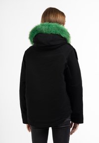 Giacca nera con collettino in pelliccia eco-cut verde. Caratterizzata da un cappuccio, maniche lunghe e tessuto testurizzato. Design classico con dettagli sottili.