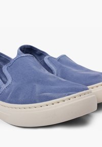 Blauwe canvas instapschoenen met elastische zijpanelen, beige rubberen zolen en witte stiksels langs de rand. Glad oppervlak over de gehele schoen.