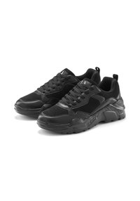 Schwarze Sneakers aus einer Kombination von synthetischem Leder und Wildleder, mit einer dicken Gummisohle, abgerundetem Zehenbereich und vorderen Schnürsenkeln für einen sicheren Sitz.