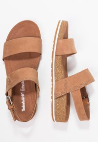 Brune semskede sandaler med to brede stropper og justerbar ankelspænde. Lysebrunt struktureret sål med en hvid detalje. Ortholite indersål.
