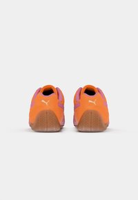 Orange und rosa Sportschuhe mit einem strukturierten Wildleder-Obermaterial, Gummisohle und einem weißen Logo an der Ferse, das ein niedrig geschnittenes Design aufweist.