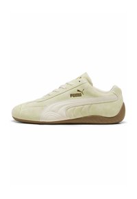Zapatillas de ante verde claro con acentos de cuero blanco, punta redondeada, suela texturizada y detalles del logo en dorado en el lateral.