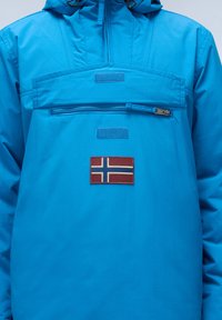 Giacca impermeabile blu con tasca frontale con zip, dotata di un patch della bandiera norvegese e tessuto testurizzato. Include cappuccio e polsini regolabili.