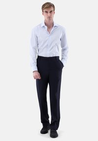 Weiß gestreiftes Langarmhemd kombiniert mit marineblauen Hosen. Das Hemd hat einen klassischen Kragen und Knopfleiste, während die Hose mit Gürtelschlaufen versehen ist.