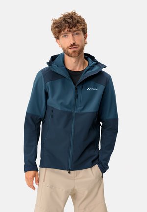 Blauwe tweekleurige softshell jack met capuchon, voorzien van ritszakken en een rits aan de voorkant. Soepel materiaal, sportieve pasvorm en subtiele logodetail.